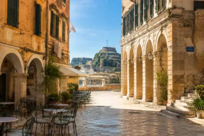 Historic Corfu Old Town street with Venetian arcades and the fortress beyond