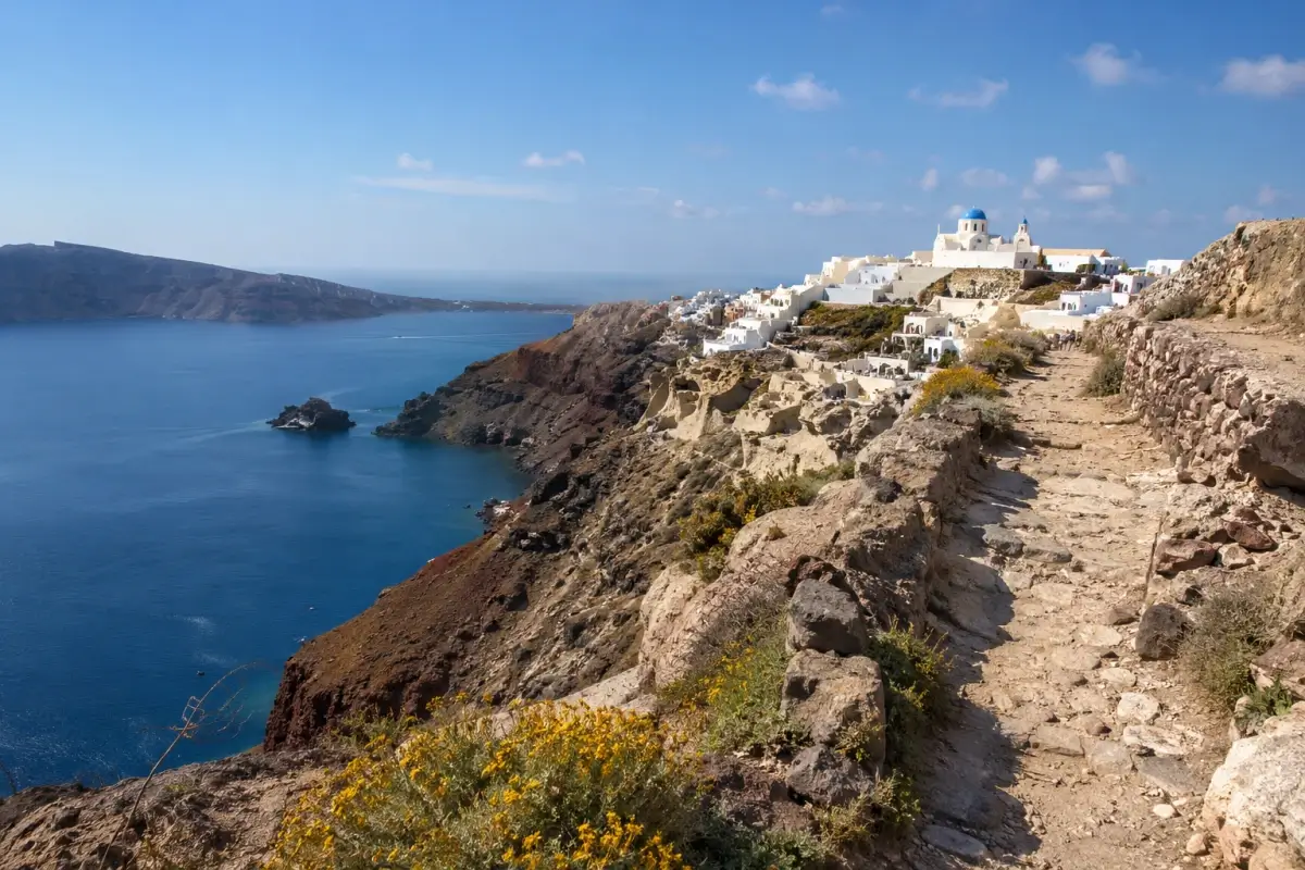 Santorini caldera hiking trail leading toward whitewashed villages and blue-domed churches
