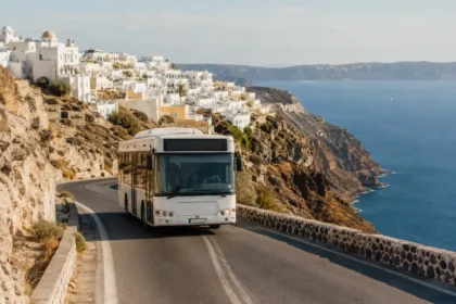 Bus driving along a cliffside road below Santorini’s caldera villages