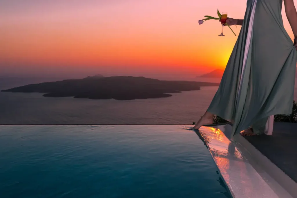 Pool edge and draped canopy overlooking the volcanic islands at sunset at Adamant Suites.