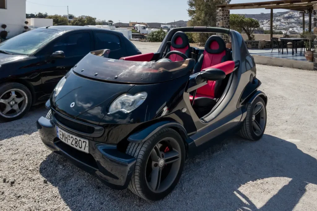 Open-top Smart Crossblade parked beside other vehicles in Akrotiri, Santorini.