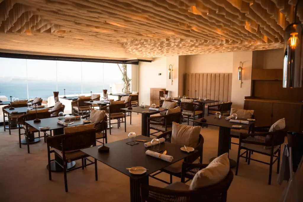 Dining room with a textured wooden ceiling and sea views at Lauda Restaurant in Oia.