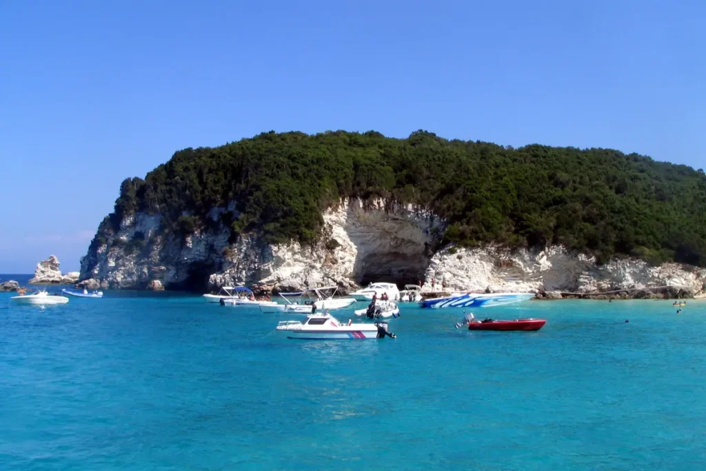 Excursion boats and smaller craft float in bright turquoise water near Vrika beach on Antipaxos
