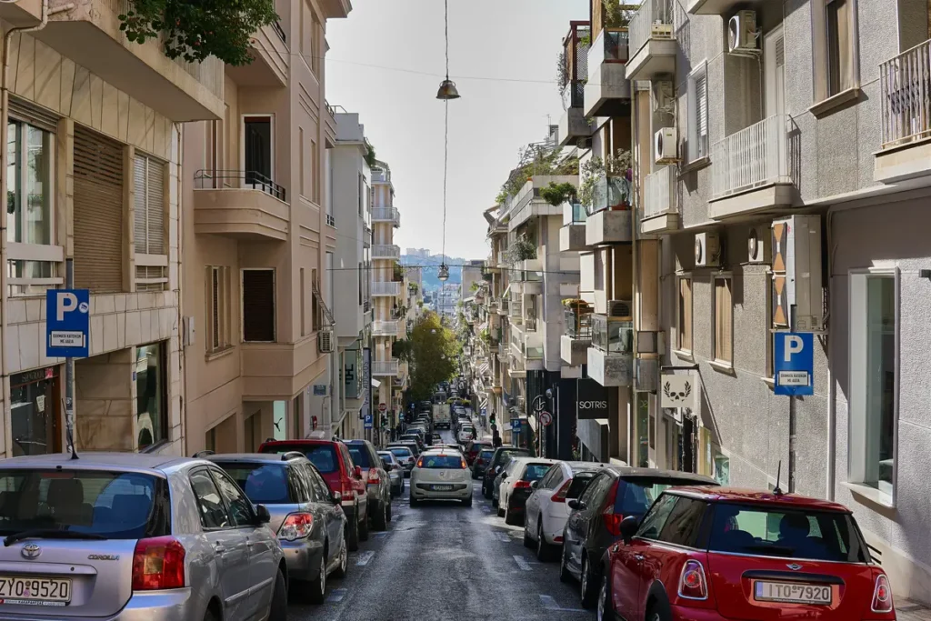 Parked cars line both sides of a sloping street in central Athens.