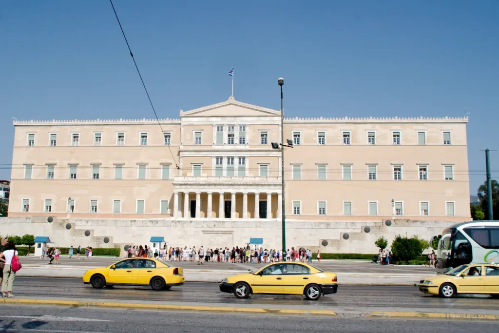 Yellow taxis pass in front of the Greek Parliament at Syntagma Square.