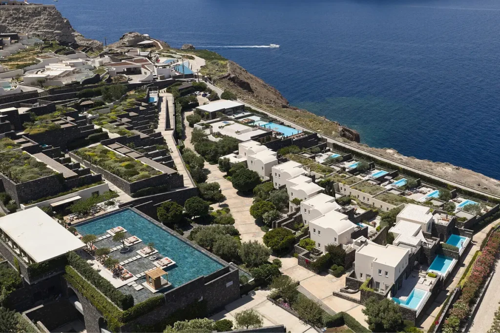 Aerial view of Canaves Epitome with pools, landscaped paths and the sea beyond.