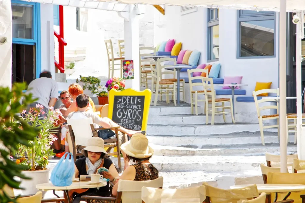 Visitors seated outside cafés along a stepped whitewashed lane in Chora, Mykonos