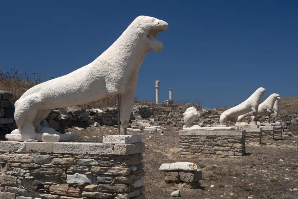 Stone lion replicas standing on plinths among the archaeological remains on Delos