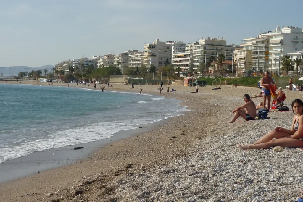 Beachgoers beside the sea at Edem, with apartment buildings lining the shore behind them.