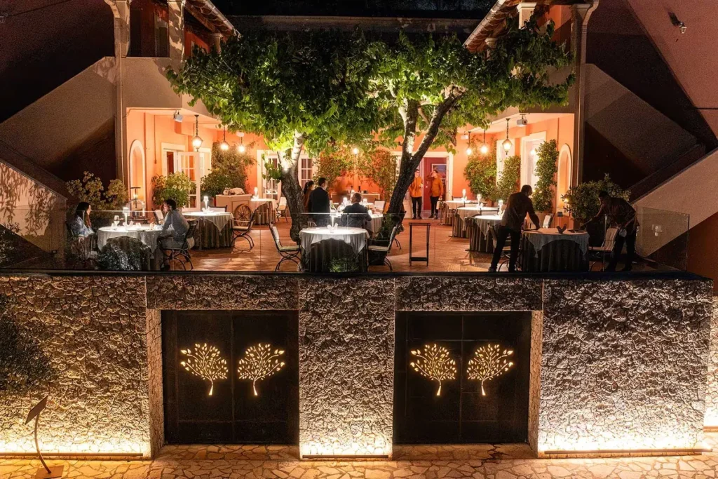 Set dining tables beneath an olive tree and warm lights in Etrusco's garden