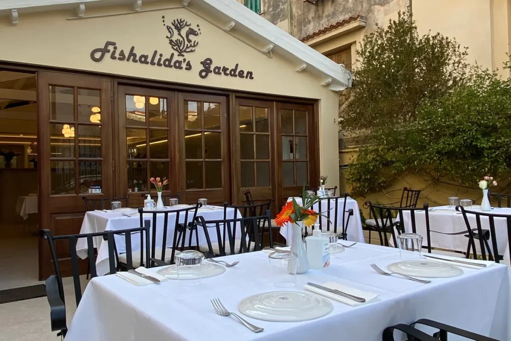 White linen-covered tables and black chairs in the courtyard outside the Fishalida's Garden entrance