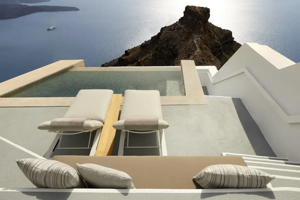 Two loungers beside a private pool overlooking Skaros Rock and the caldera at Grace Hotel in Santorini.