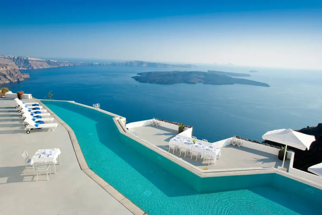 Angular infinity pool and white dining terraces overlooking the caldera at Grace Hotel, Santorini.