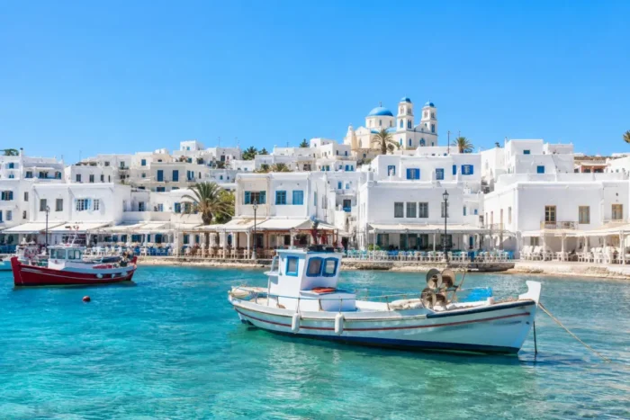 Whitewashed Greek island harbor with fishing boats, waterfront tavernas, and clear blue water