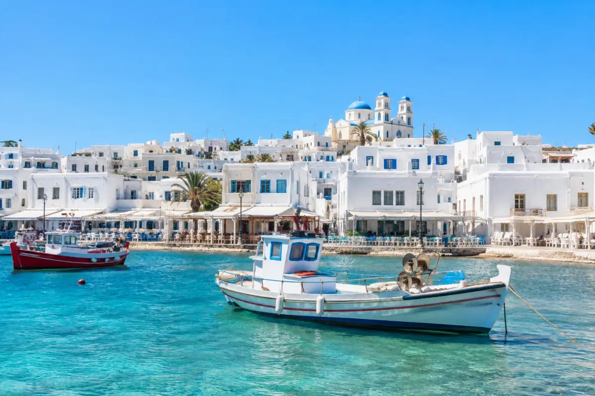 Whitewashed Greek island harbor with fishing boats, waterfront tavernas, and clear blue water