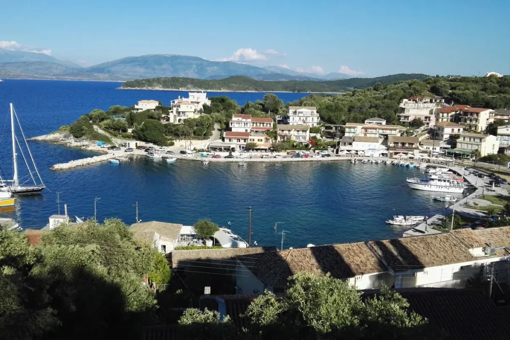 Sailboats and small craft moored in Kassiopi's harbor beside waterfront buildings