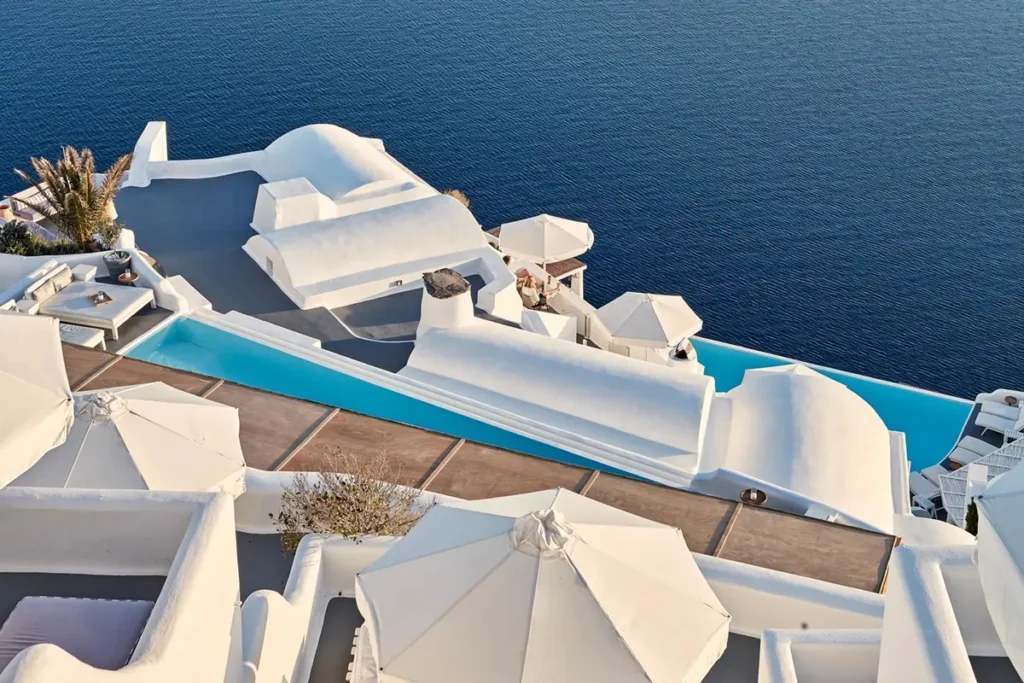 Long turquoise pool surrounded by whitewashed terraces above the sea at Katikies Santorini.