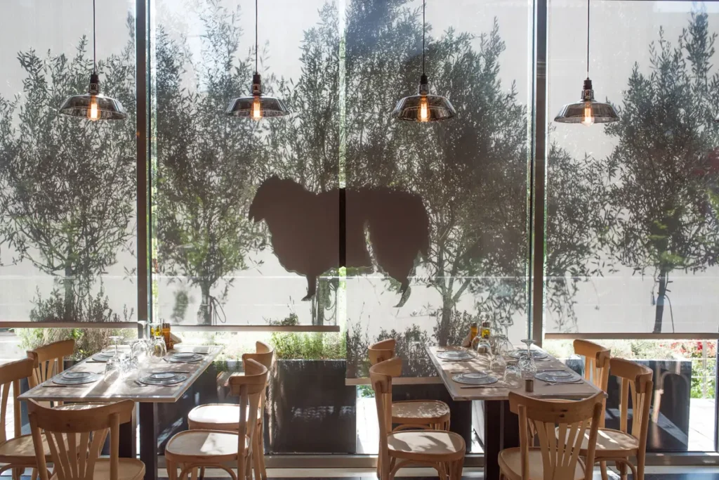 Wooden tables, glass frontage and the black sheep motif in Mavro Provato’s dining room.