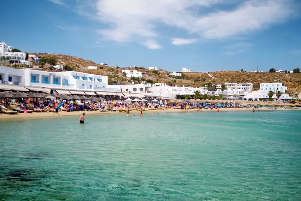 Clear blue water and a sandy beach lined with white buildings at Platis Gialos in Mykonos