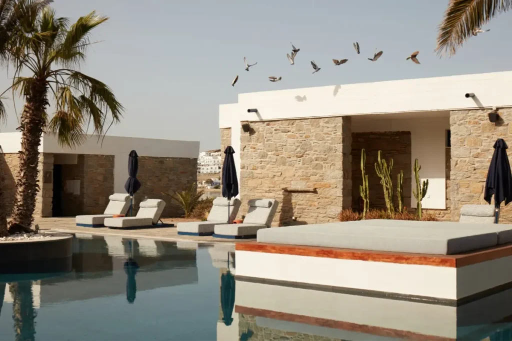 Low stone-and-white hotel buildings beside the swimming pool at Mykonos Theoxenia
