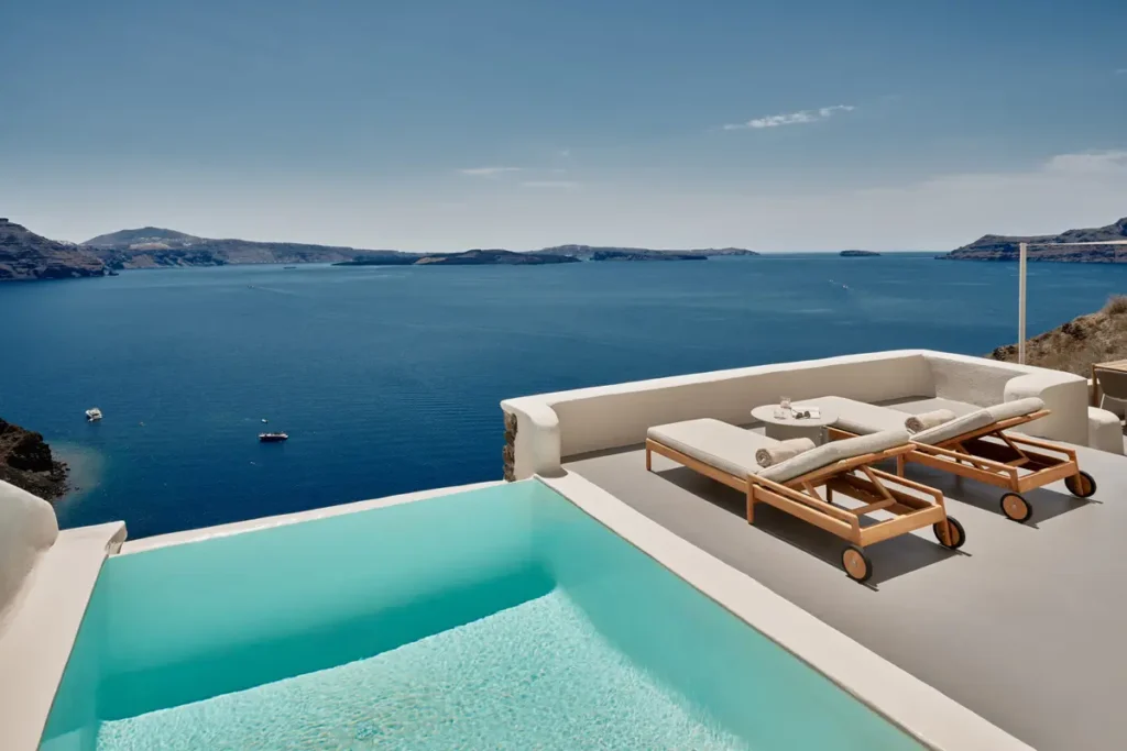 Two sun loungers beside a pool overlooking the sea at Mystique in Oia.