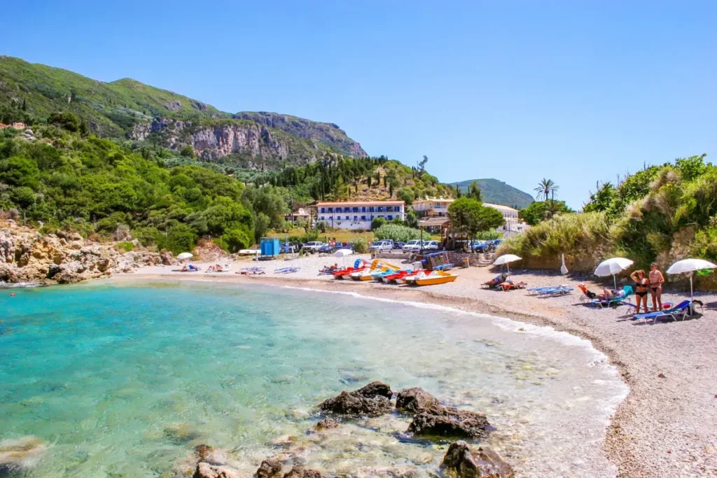 A sheltered beach with clear water, small boats and wooded slopes in Paleokastritsa