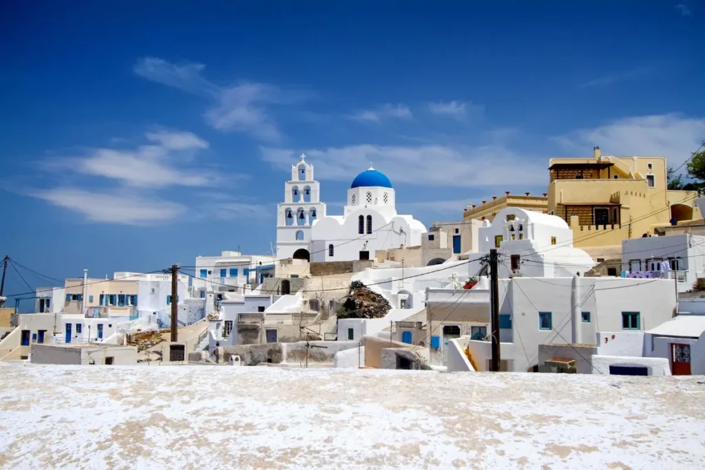 White hillside buildings and a blue-domed church in Pyrgos, Santorini.