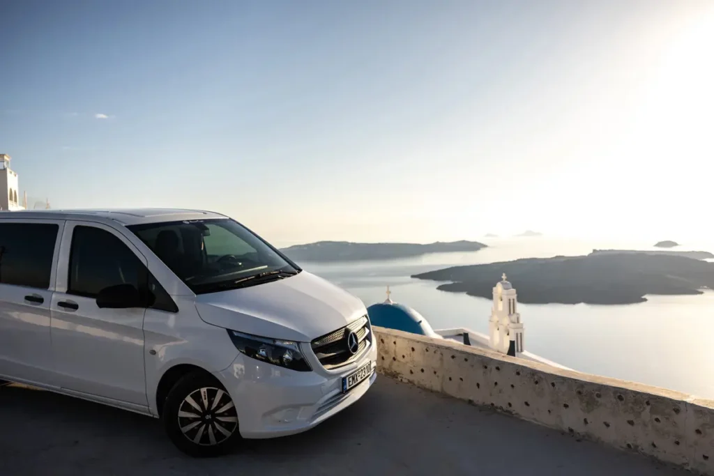 White passenger van parked beside a caldera viewpoint in Santorini.