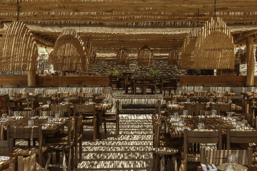 Wooden tables and woven chairs beneath a reed-covered roof in Scorpios's restaurant