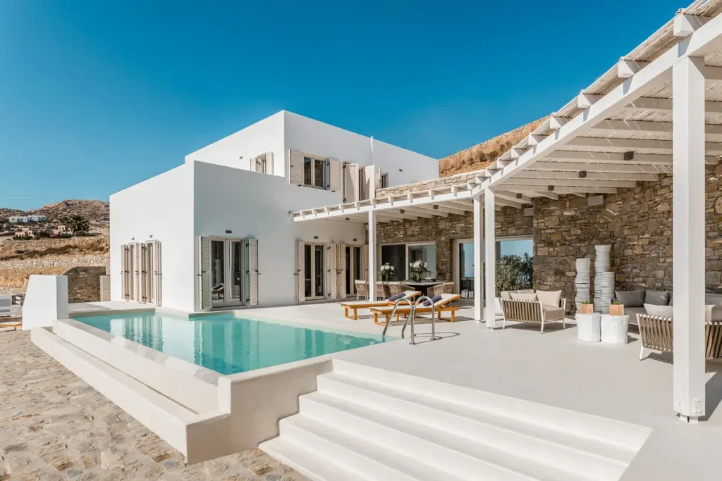 White villa and stone wall beside a pale-blue pool and shaded terrace at Sea Gaze