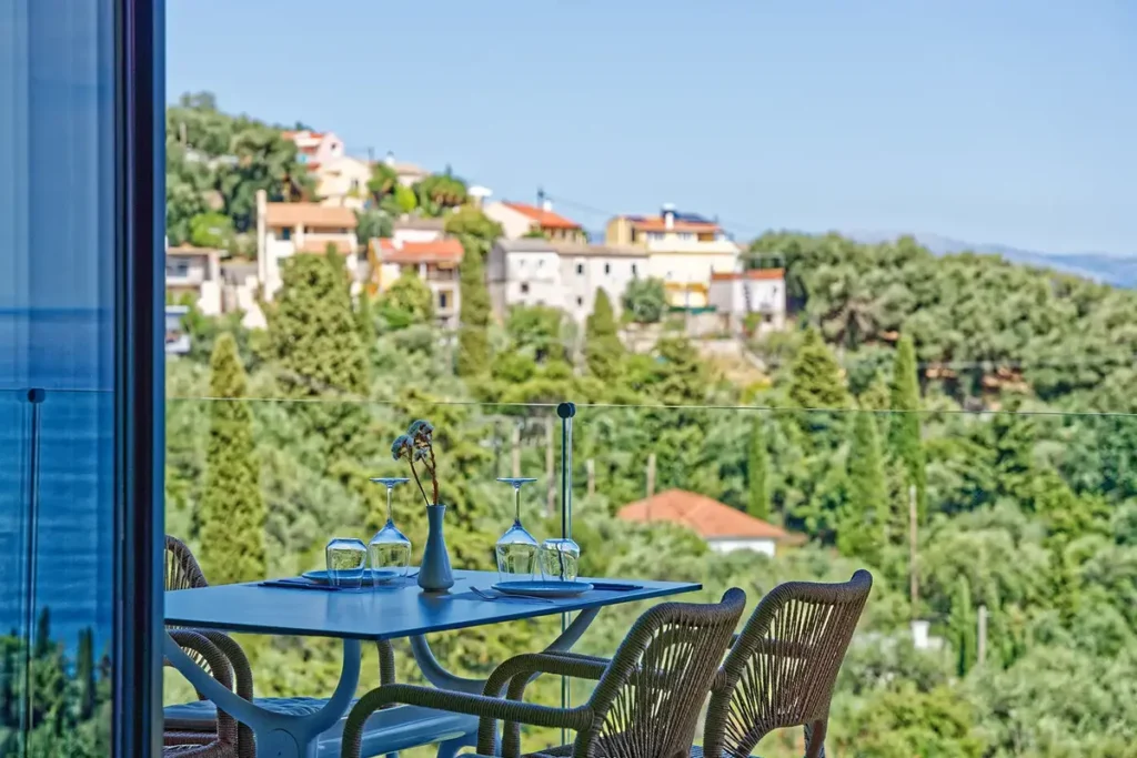 A table beside an open window overlooks green hills and neighboring buildings at Terra Corfiata