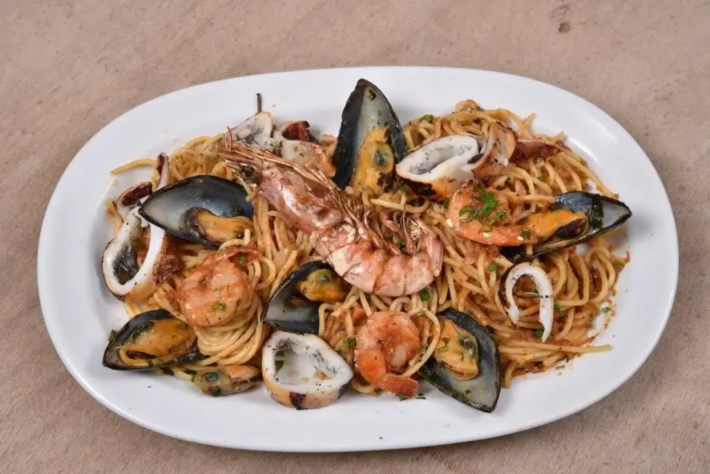 Seafood pasta with prawns and shellfish on a white plate at The Cave of Nikolas.