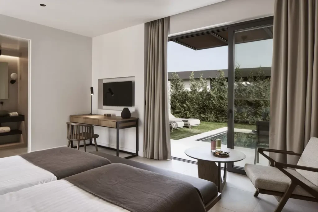 A bright suite opens through sliding glass doors onto a planted terrace with outdoor seating