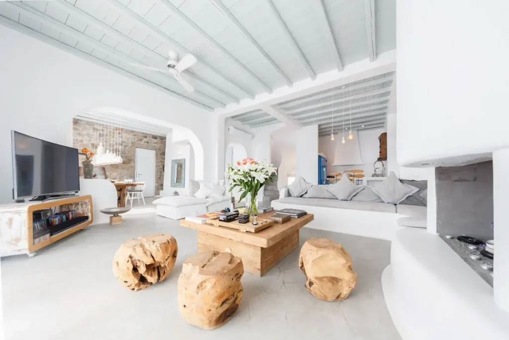 Bright white living room with built-in sofas, a wood coffee table and large openings at Villa Callista