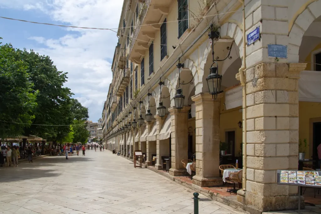 People walk along the paved promenade beside Liston's arcaded stone buildings