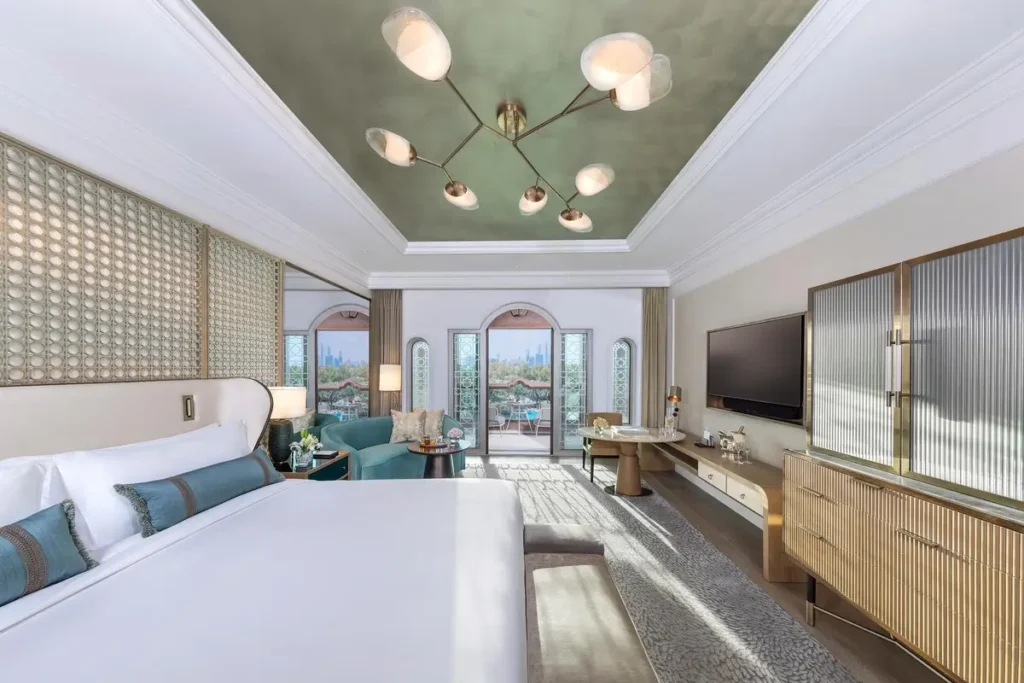 Bed, seating area, television, and balcony doors in a Deluxe Garden View Room at Emirates Palace Mandarin Oriental, Abu Dhabi.