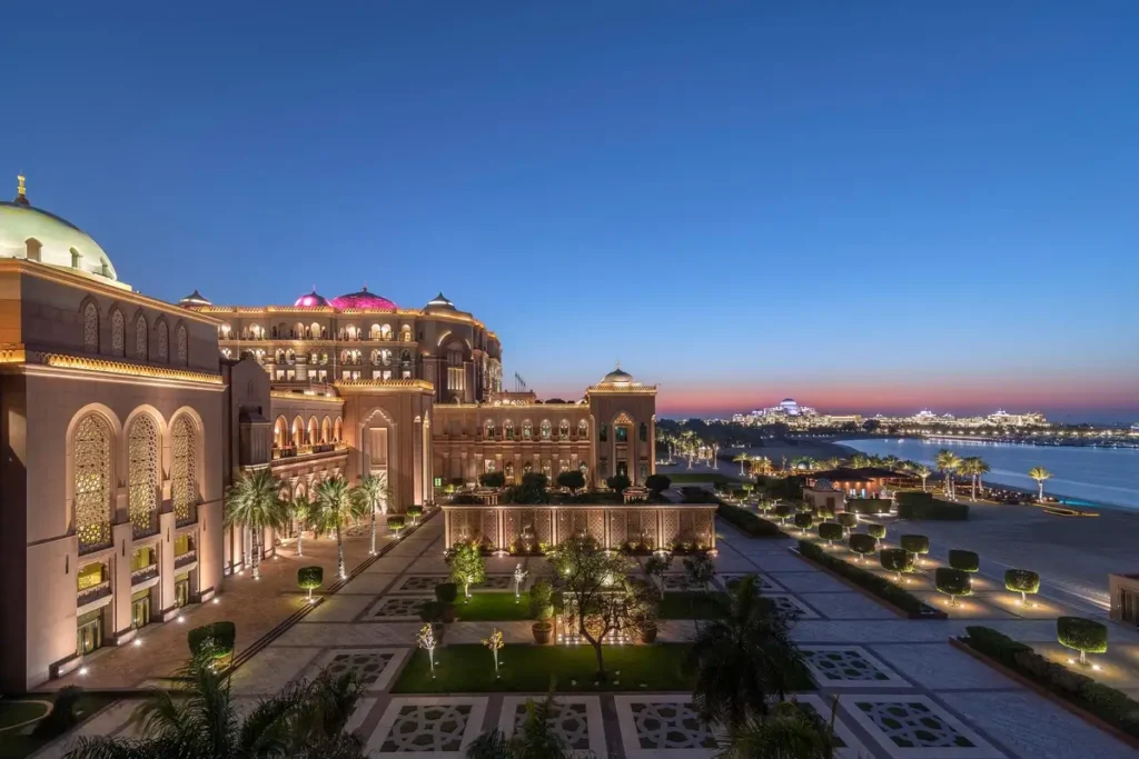 Illuminated palace wings, landscaped grounds, and waterfront at dusk at Emirates Palace Mandarin Oriental, Abu Dhabi.