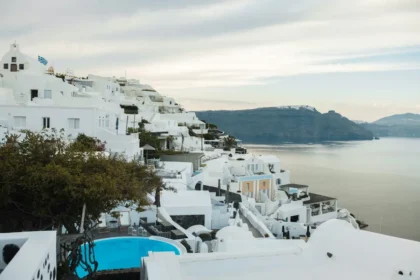 Whitewashed buildings and a blue pool above the caldera in Oia, Santorini.