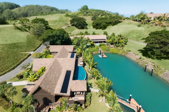 Aerial view of a thatched residence with a pool beside a turquoise marina at Six Senses Fiji