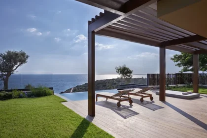 Shaded wooden villa terrace with loungers, lawn, and a view of the sea at Six Senses Kaplankaya