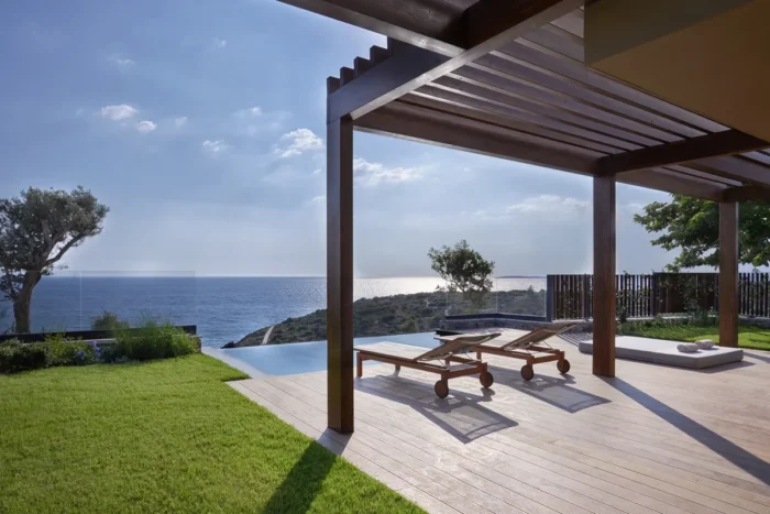 Shaded wooden villa terrace with loungers, lawn, and a view of the sea at Six Senses Kaplankaya