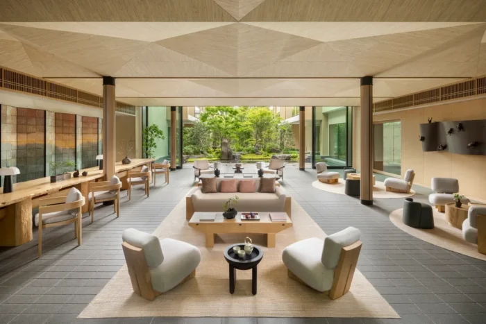 Spacious lobby with pale armchairs, timber furniture, and windows facing a green garden at Six Senses Kyoto
