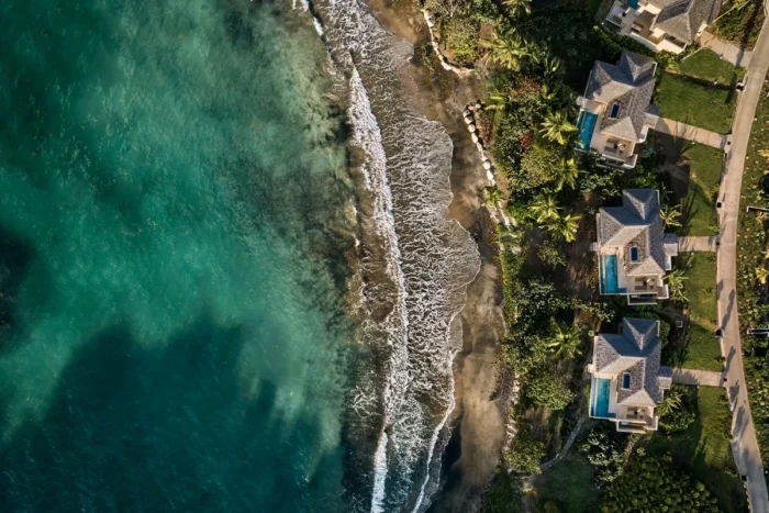 Overhead view of villas and palms beside a narrow beach and green-blue sea at Six Senses La Sagesse