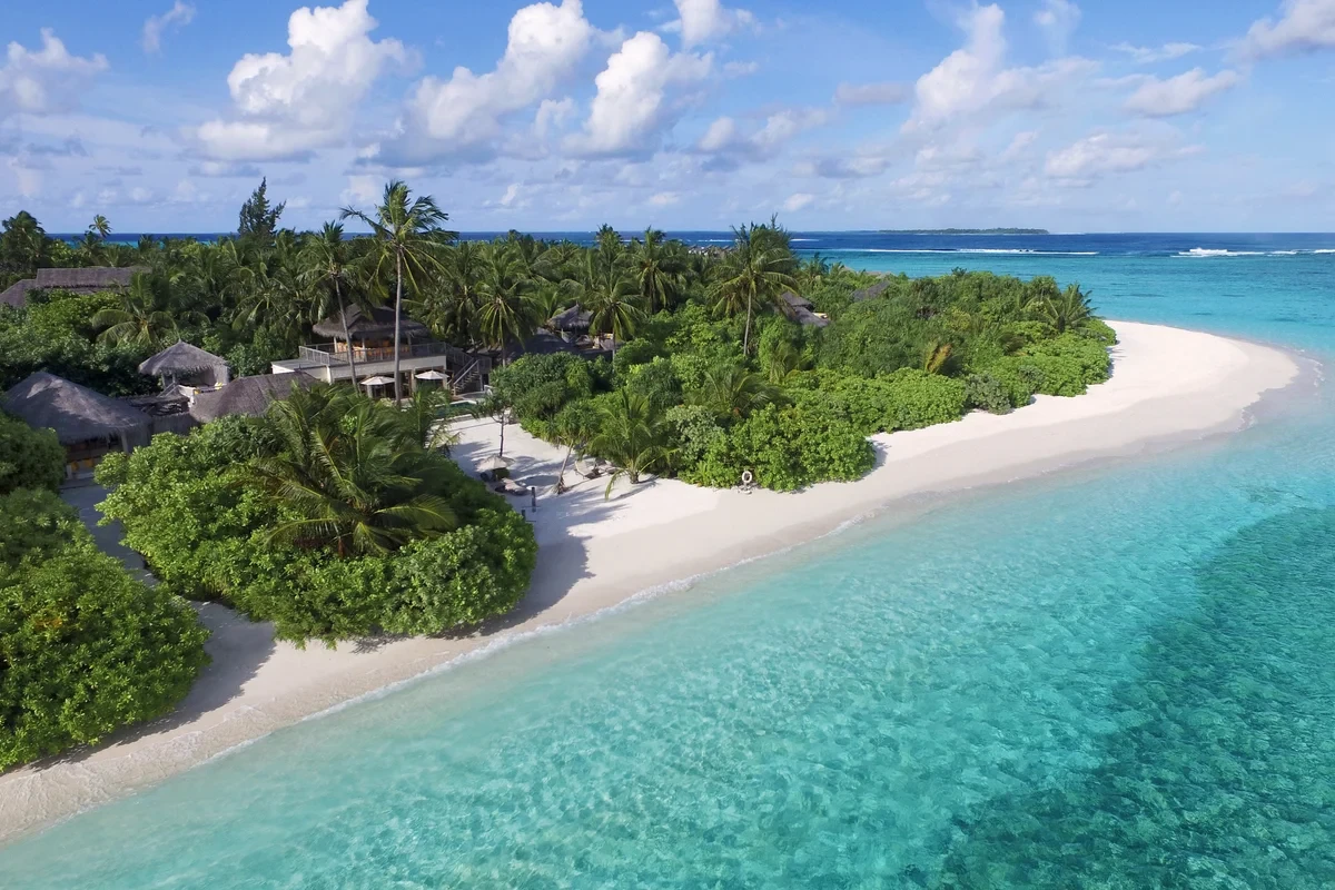 Aerial view of a palm-covered beachfront with white sand and a turquoise lagoon at Six Senses Laamu