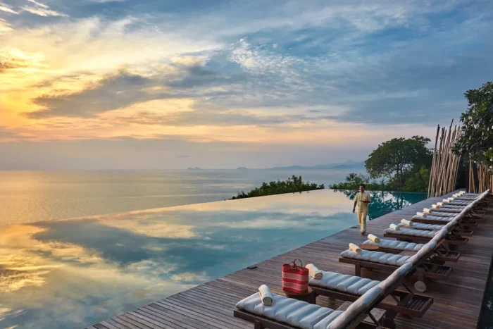 Infinity pool reflecting the sunset beside a row of sun loungers overlooking the sea at Six Senses Samui