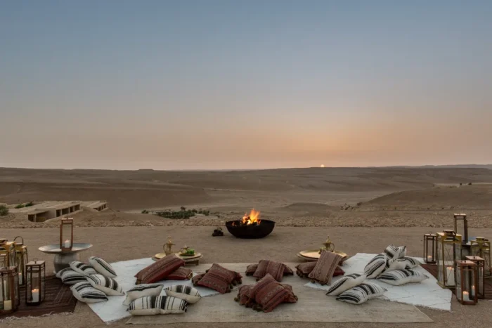 Floor cushions and lanterns around a fire bowl on a terrace overlooking the desert at Six Senses Shaharut