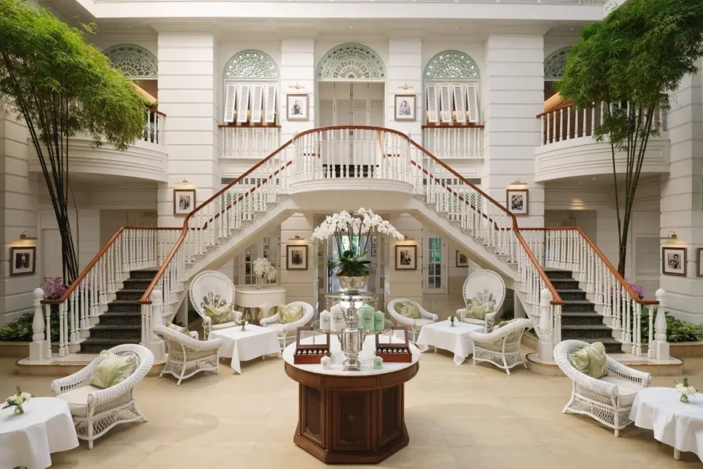 White wicker seating, climbing plants, and a symmetrical staircase in the Authors’ Lounge at Mandarin Oriental, Bangkok.