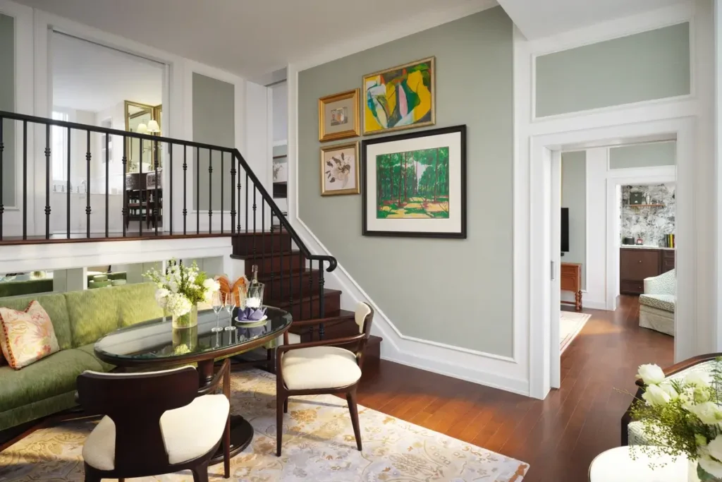 Green sofa, armchairs, and an internal staircase in the split-level Chao Phraya Suite at Mandarin Oriental, Bangkok.