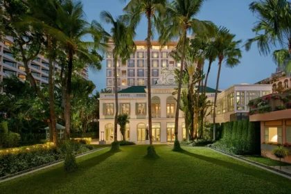 Palm trees frame the illuminated historic facade and hotel tower at Mandarin Oriental, Bangkok.