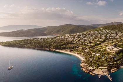Aerial view of Mandarin Oriental, Bodrum spreading across a wooded hillside above a curved Aegean bay.